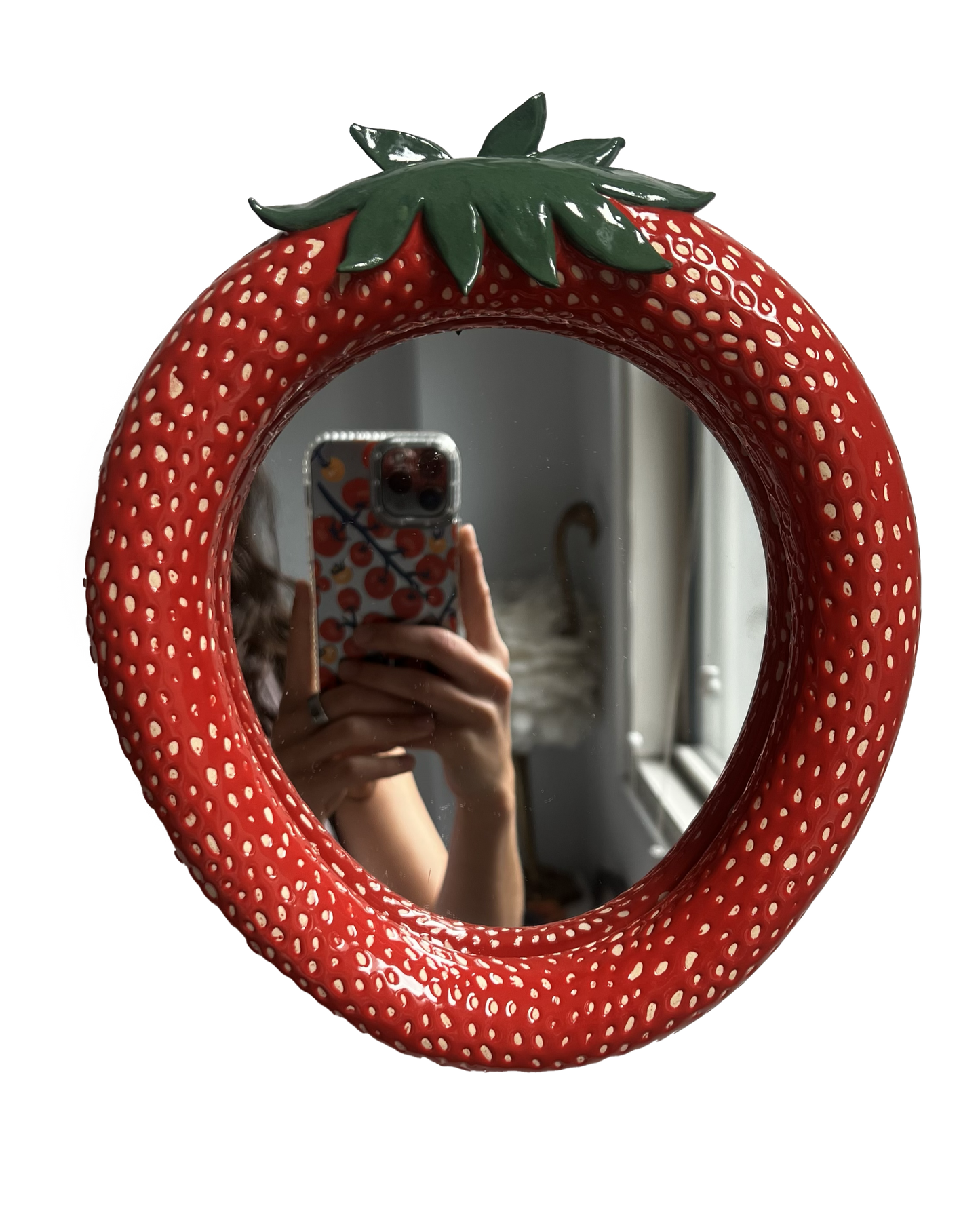 Strawberry-shaped mirror with a green stem on a white background. handmade ceramic mirror made in new york city