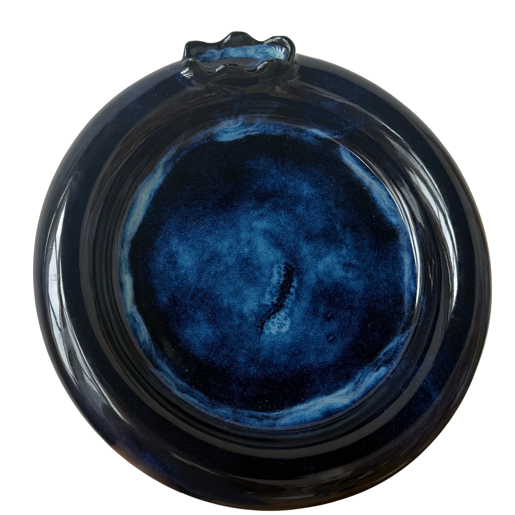 A round ceramic plate with a glossy dark blue and black marbled glaze, featuring a small decorative protruding handle at the top, shown against a plain white background.
