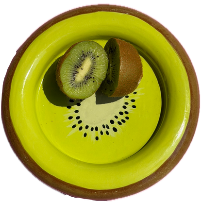 A round kiwi shaped ceramic plate with a bright lime green interior and a brown rim, shown from above with two halves of a sliced kiwi fruit placed inside the plate on a white background.