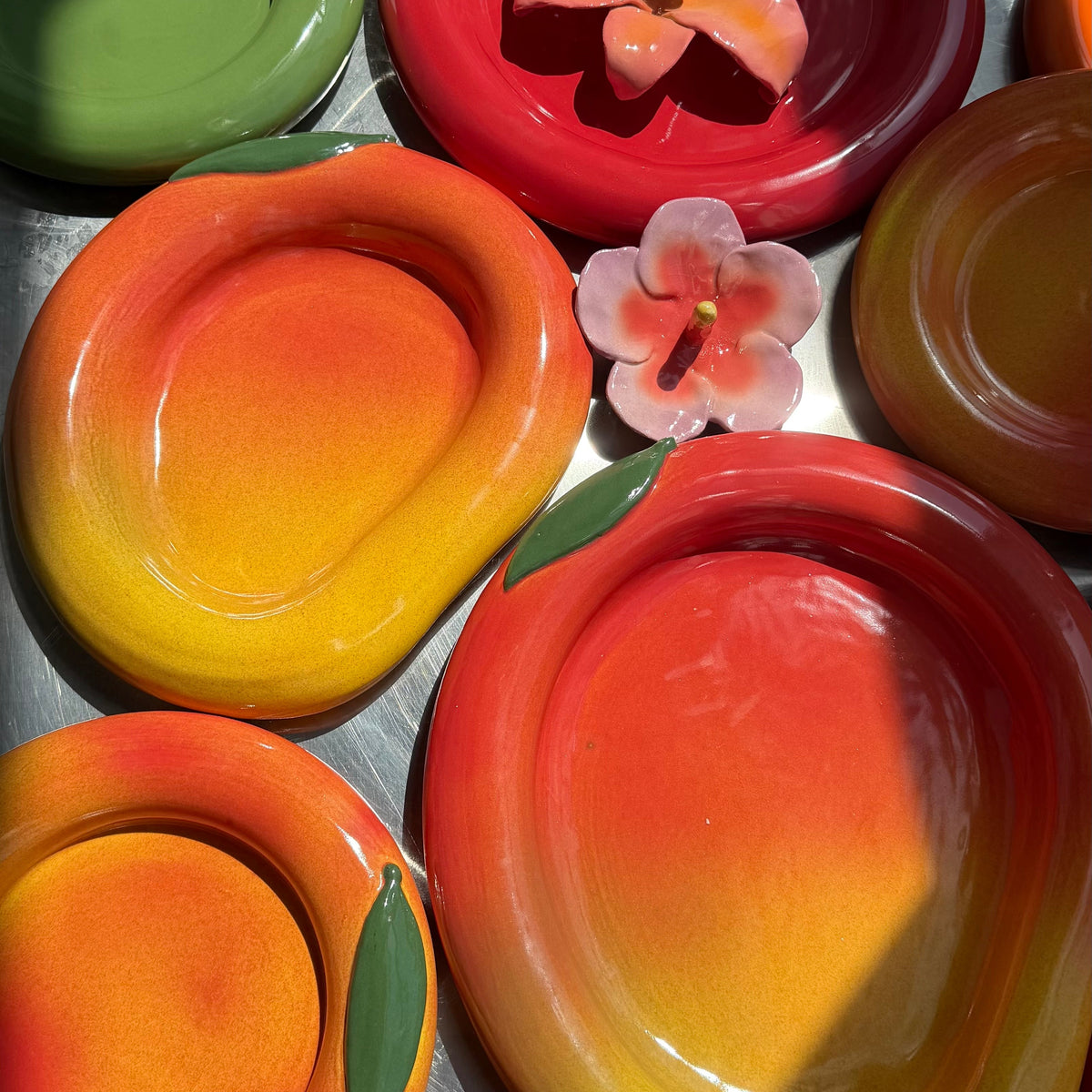 Colorful mango ceramic bowls with floral decorations on a metal surface