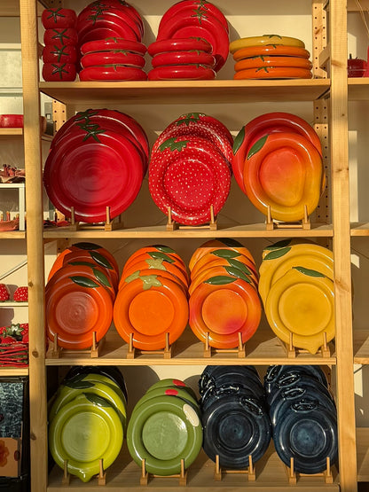Shelves displaying a variety of colorful ceramic plates on a wooden rack.