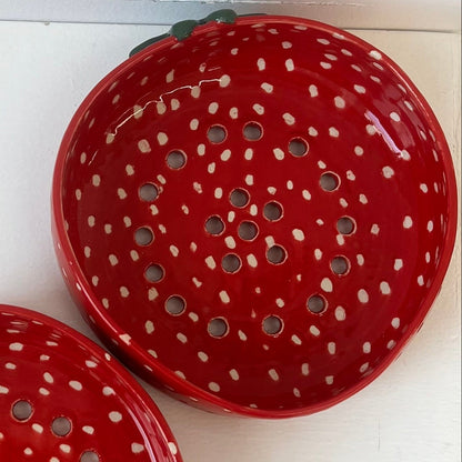 Two red ceramic items with holes on a white surface.